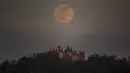 Supermoon merah muda terlihat di atas Kastil Belvoir, Leicestershire, Inggris, Selasa (7/4/2020). Fenomena dimana bulan berada pada titik terdekat dengan bumi ini merupakan penampakan supermoon terbesar di tahun 2020. (Danny Lawson/PA viaAP)