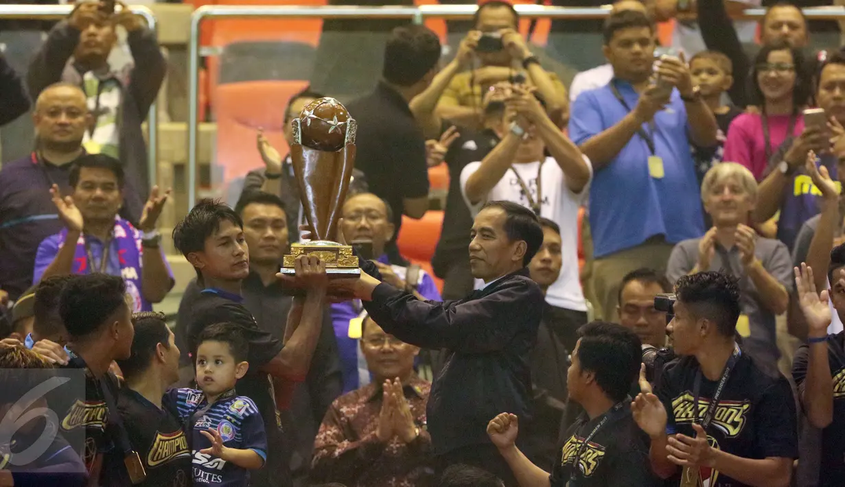 Presiden Joko Widodo menyerahkan trofi kepada Kapten tim Arema FC, Johan Ahmat Farizi usai final di Stadion Pakansari, Kab Bogor, Minggu (12/3). Arema menang 5-1 atas PBFC dan berhasil merengkuh trofi Piala Presiden. (Liputan6.com/Helmi Fithriansyah) 
