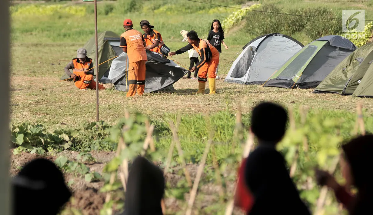 Warga menyaksikan petugas PPSU mendirikan tenda saat persiapan untuk doa bersama pada malam Tahun Baru di Cipinang Melayu, Jakarta, Minggu (30/12). (Merdeka.com/ Iqbal S. Nugroho)