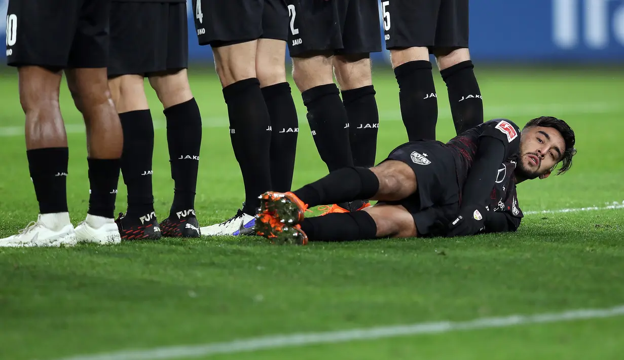 Striker VFB Stuttgart, Nicolas Gonzalez berbaring di belakang rekan-rekannya yang membuat pagar hidup untuk menjaga tendangan bebas yang dilakukan pemain Wolfsburg dalam laga lanjutan Liga Jerman 2020/21 di Volkswagen Arena, Minggu (20/12/2020). (AFP/Ronny Hartmann)
