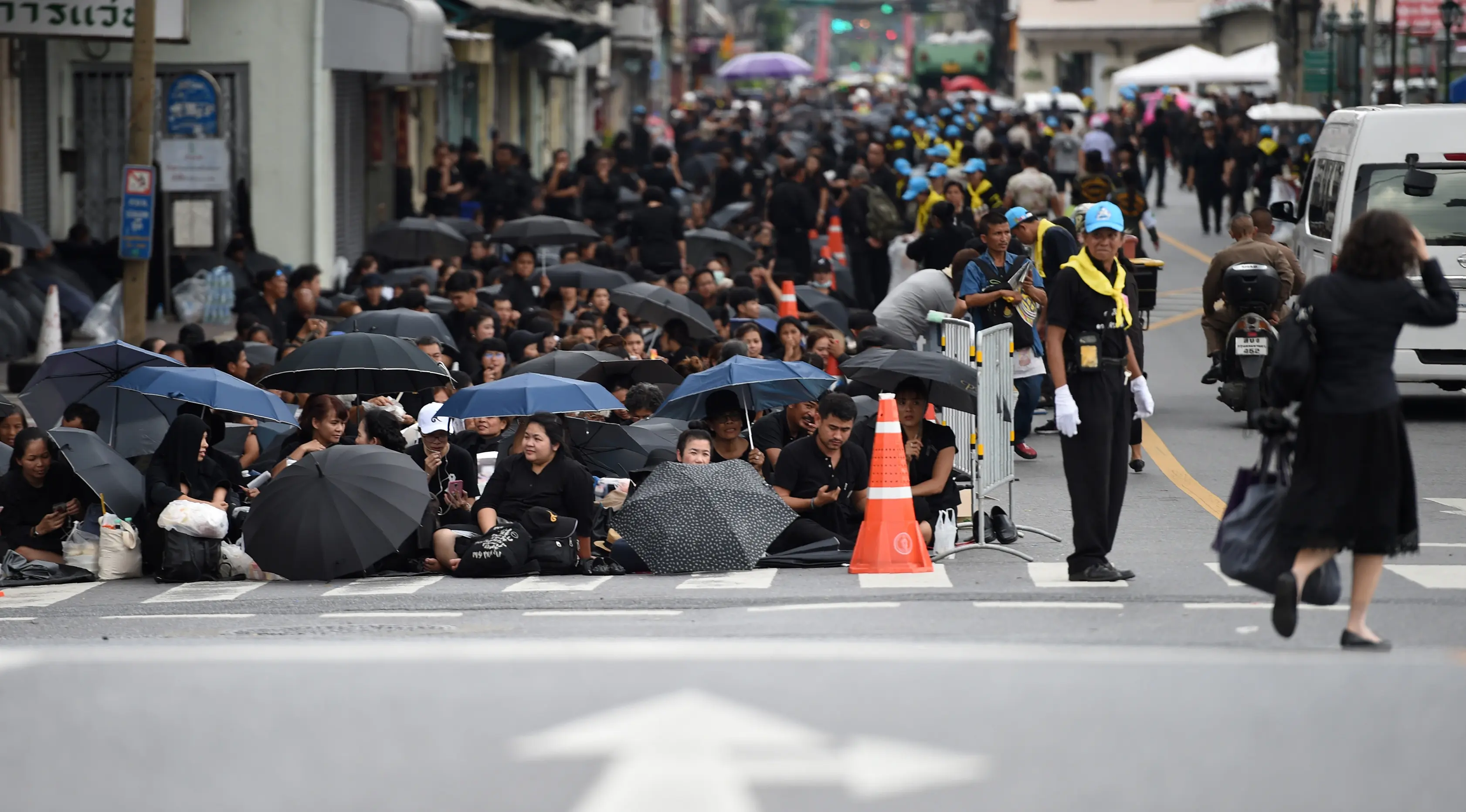 Sejumlah warga mengenakan pakaian hitam memadati jalan saat saat menunggu pemakaman mendiang Raja Thailand Bhumibol Adulyadej di Bangkok (25/10). (AFP Photo/Anthony Wallace)