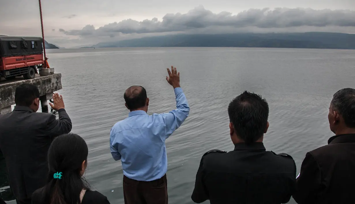 Keluarga dan warga berdoa untuk penumpang yang hilang dari kecelakaan KM Sinar Bangun di Danau Toba di Pelabuhan Tigaras, Sumut, Indonesia (21/6). Kapal kayu ini memiliki kemampuan mengangkut 43-80 diduga kelebihan penumpang. (AFP Photo/Ivan Damanik)