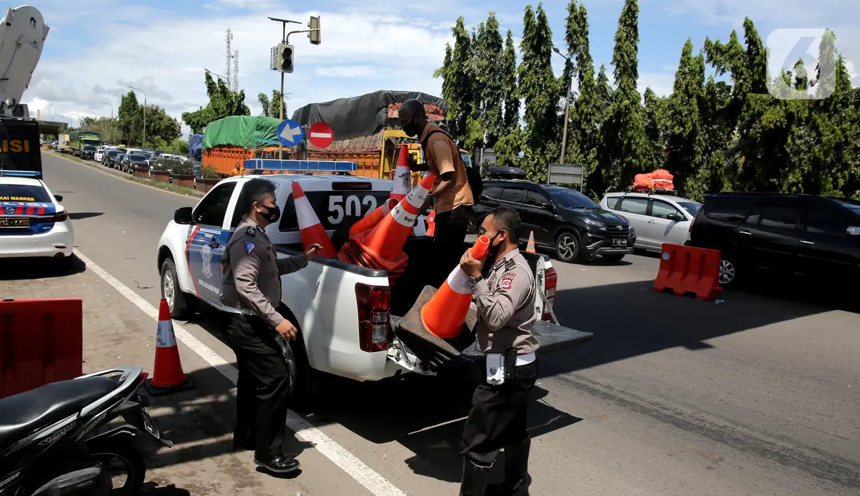 <p>Polisi menurunkan pembatas jalan dari mobil saat melakukan sistem buka tutup jalan menuju Pelabuhan Merak, Cilegon, Banten, Jumat (29/4/2022). Sistem buka tutup tersebut membuat kemacetan panjang hingga ke dalam Tol Tangerang-Merak. (Liputan6.com/Angga Yuniar)</p>
