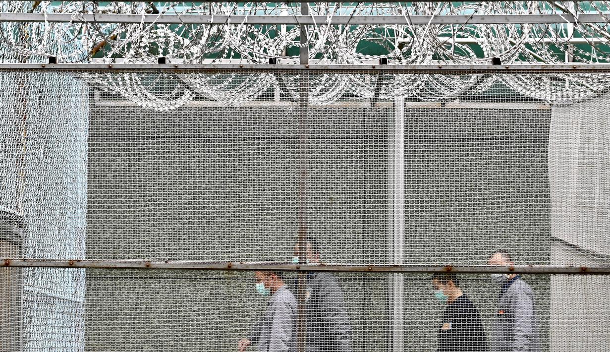 Para tahanan mengenakan masker berjalan di belakang pagar dan kawat berduri di Penjara Taipei di Kota Taoyuan, Taiwan utara (10/3/2020). Penyebaran virus corona semakin meluas ke berbagai negara di seluruh dunia. (AFP/Sam Yeh)