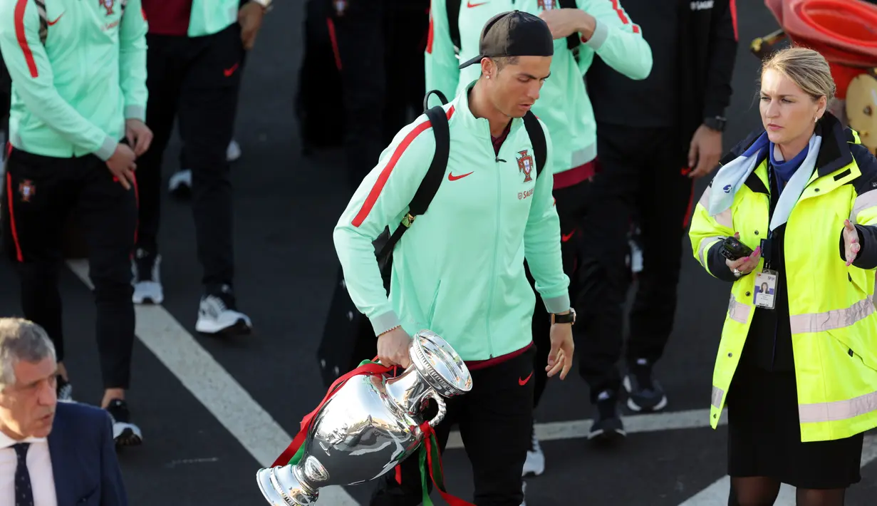 Pemain sepak bola Portugal, Cristiano Ronaldo membawa trofi Euro 2016 saat tiba di bandara Medeira, Portugal (27/3). Ronaldo bersama timnas Portugal akan melakukan pertandingan persahabatan dengan timnas Swedia. (AP Photo/Armando Franca)