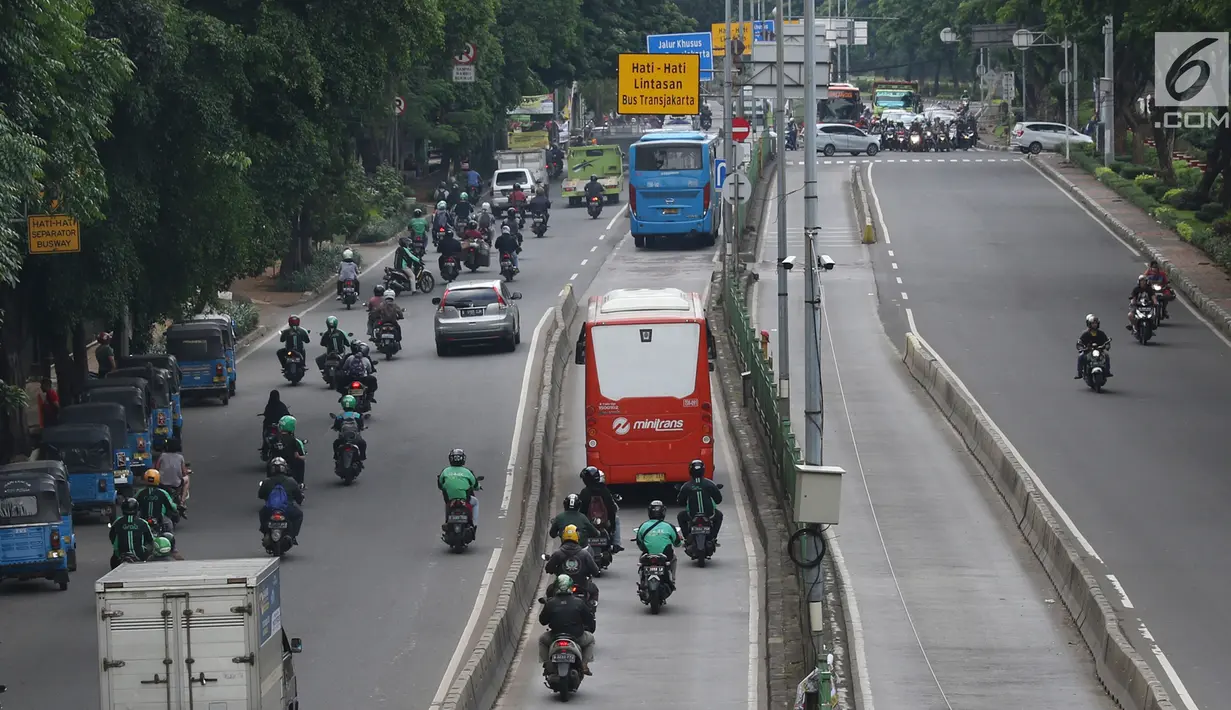 Pengendara motor melaju di belakang bus Transjakarta di kawasan Pasar Rumput, Jakarta, Rabu (20/2). PT Transportasi Jakarta akan memasang kamera pengawas (CCTV) di setiap halte untuk menerapkan tilang online atau E-Tilang. (Liputan6.com/Immanuel Antonius)