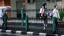 Seorang wanita melompati pagar pembatas di Stasiun Cikini, Jakarta, Rabu, (20/12). Banyaknya penumpang yang mencari jalan pintas dengan melompat pagar untuk menuju akses pintu keluar menyebabkan kemacetan di kawasan stasiun. (Liputan6.com/Johan Tallo)