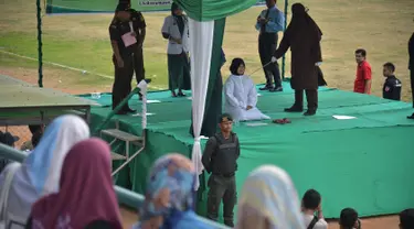 Seorang wanita dicambuk setelah ketahuan melakukan hubungan seks pranikah di sebuah stadion di Lhokseumawe di provinsi Aceh (31/7/2019). Dua pria dan seorang wanita dicambuk secara terbuka sebanyak 100 kali karena melanggar hukum Islam di daerah tersebut. (AFP Photo/Rahmad Mirza)