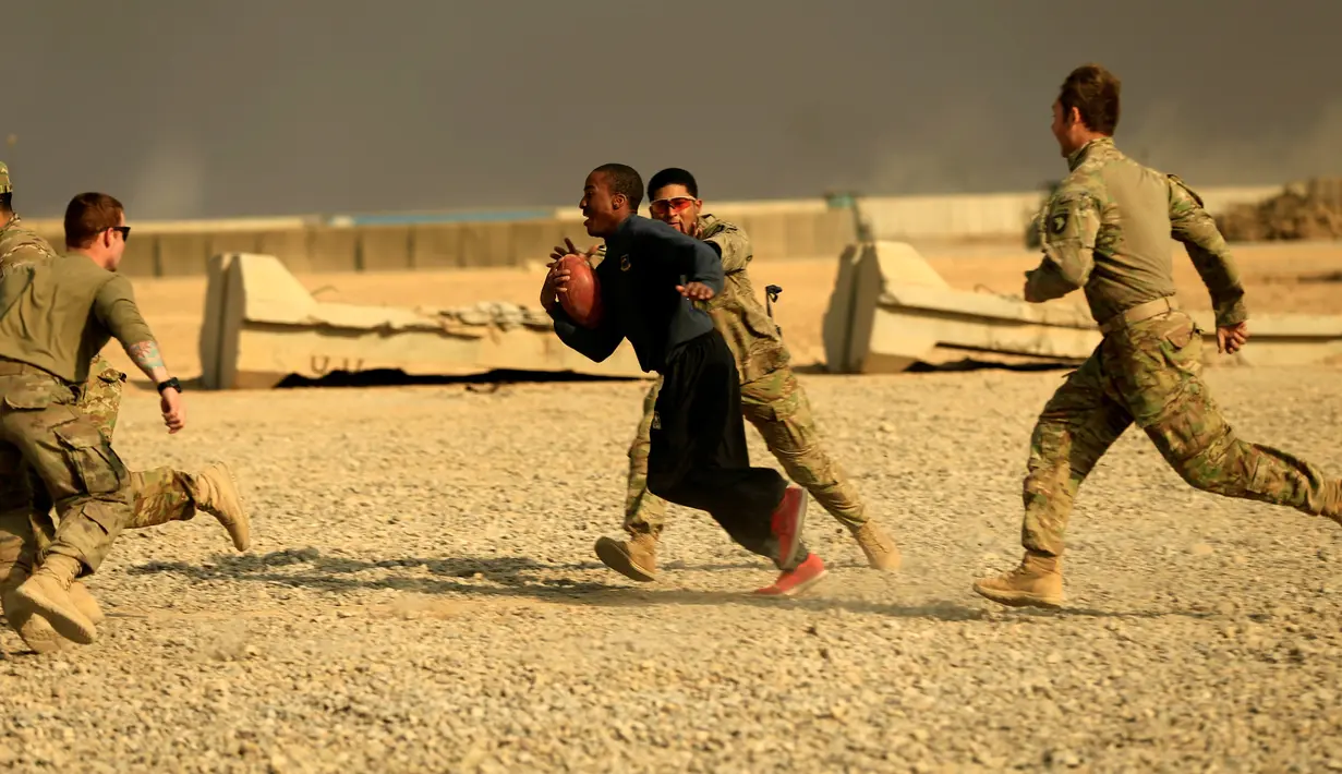Tentara AS berlari membawa bola saat bermain American Football pada Thanksgiving di dalam pangkalan militer AS di Qayyara, selatan Mosul, Irak (24/141). (REUTERS/Thaier Al-Sudani)