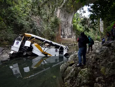 Awak media mengambil gambar sebuah bus berisi anggota tim sepak bola yang terjun ke jurang dari sebuah jembatan di Negara Bagian Veracruz, selatan Meksiko, Minggu (10/1). Sedikitnya 20 orang penumpang tewas dalam kecelakaan ini. (REUTERS/Yahir Ceballos)