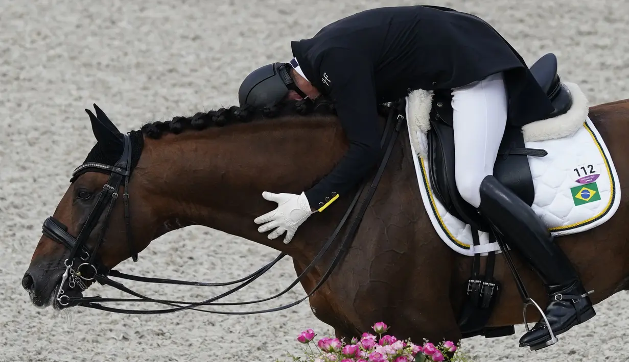 Joao Victor Marcari Oliva dari Brasil, memeluk Escorial Horsecampline saat berselebrasi setelah kompetisi Grand Prix dandanan Olimpiade Tokyo 2020 di Equestrian Park pada 24 Juli 2021, di Tokyo, Jepang. (AP Photo /Carolyn Kaster)