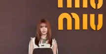 Momo TWICE tampil dengan gaya playful bernuansa vintage. Ia mengenakan mini dress cokelat bersiluet babydoll yang dipadukan dengan panel rajut krem pada bagian atas. Aksen scarf bermotif warna-warni di leher menambah sentuhan retro yang khas. [Dok/Miu Miu].
