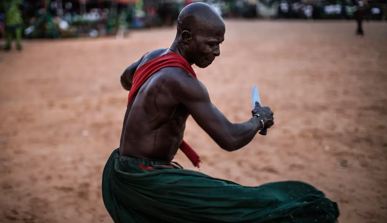 Atraksi seorang warga etnis Joles menggunakan pisau tajam di Bikama, Gambia (24/11). Atraksi ini menunjukan kekuatan sihir yang berasal dari air spritual yang membuat mereka kebal dari senjata tajam. (AFP/Marco Longari)