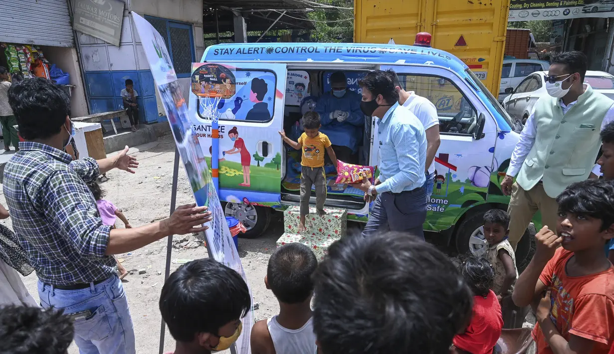 Sukarelawan memberikan makanan ringan kepada anak laki-laki setelah memberikan sampel swab untuk menguji virus corona Covid-19 di dalam sebuah van di New Delhi, India (1/7/2021).  Kegiatan ini diselenggarakan oleh Polisi Delhi bekerja sama dengan lab Star Imaging and Path. (AFP/Prakash Singh)