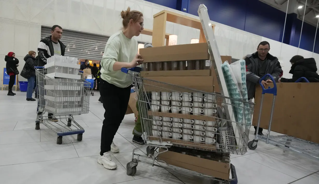 Orang-orang membawa pembelian mereka saat toko IKEA tutup di pinggiran St. Petersburg, Kamis (3/3/2022). Peritel IKEA menghentikan operasional di "Negeri Beruang Merah" dan Belarusia untuk sementara waktu mulai Jumat, 4 Maret 2022 buntut dari invasi Rusia ke Ukraina. (AP Photo/Dmitri Lovetsky)