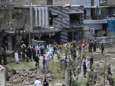 Petugas polisi, penyelidik, dan petugas penyelamat berkumpul di lokasi ledakan, di Lahore, Pakistan, Rabu (23/6/2021). Ledakan itu terjadi sekitar 120 meter dari kediaman Hafiz Saeed di Lahore, menurut laporan. (AFP/Arif Ali)