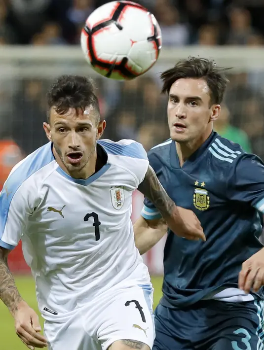 Gelandang timnas Uruguay Brian Lozano berebut bola dengan bek timnas Argentina Nicolas Tagliafico dalam laga persahabatan di Stadion Bloomfield, Tel Aviv, Israel, Senin (18/11/2019). Skor berakhir 2-2, dengan penalti Lionel Messi menghindarkan timnas Argentina  dari kekalahan. (Jack GUEZ/AFP)