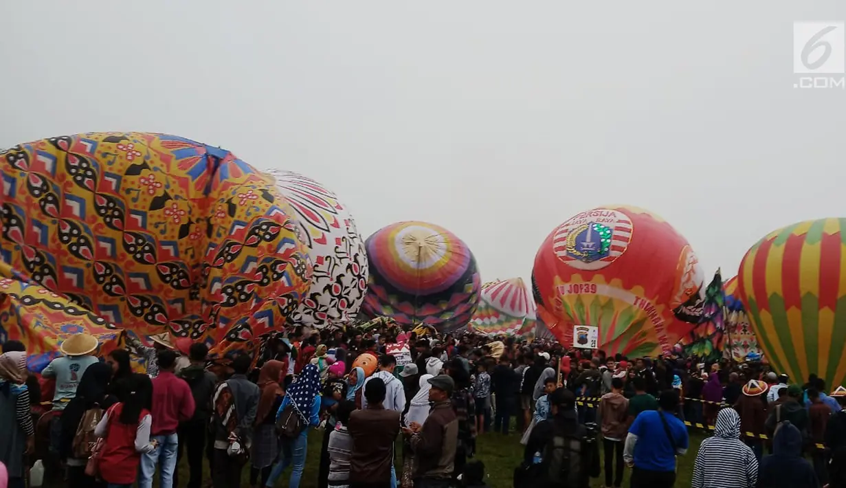 Sejumlah warga bersiap melihat balon udara dinaikan di Lapangan Pagerejo, Kertek, Kabupaten Wonosobo,  Sabtu (15/6/2019). Festival ini untuk memeriahkan syawalan dan wujud syukur warga yang hidup di lereng gunung sindoro dan sumbing. (Liputan6.com/Gholib)