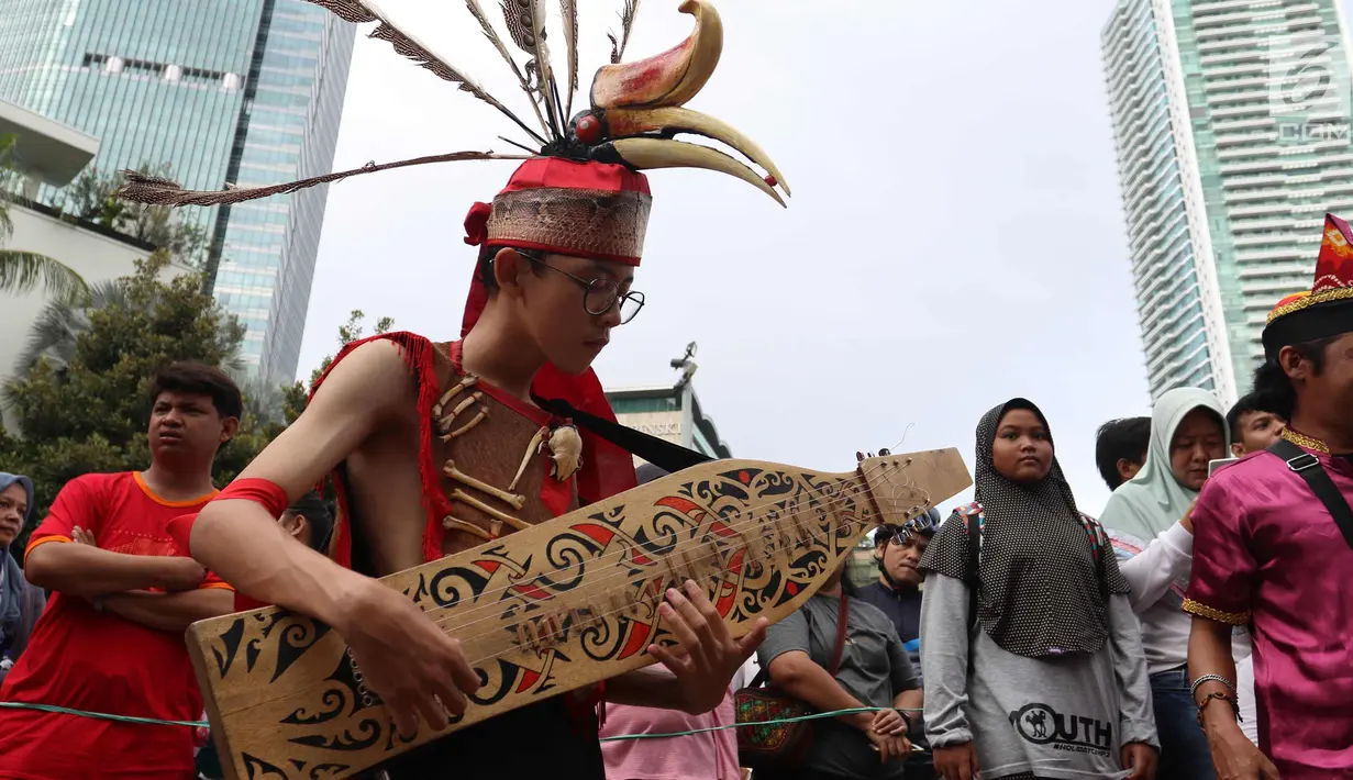 Seorang pria memainkan alat musik tradisional saat CDF di Jakarta, Minggu (28/1). Tarian tersebut dilakukan dalam rangka festiival etnik Tabalong agar masyarakat mengenal tarian yang berasal dari  Kalimantan Selatan tersebut. (Liputan6.com/Angga Yuniar)