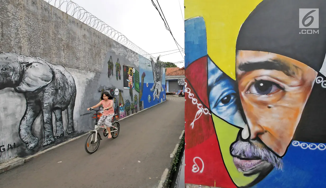 Seorang bocah bermain sepeda di antara dinding berhias mural bertema Islami di Gang Abdul Jabar, Jagakarsa, Jakarta, Senin (28/5). (Liputan6.com/Herman Zakharia)