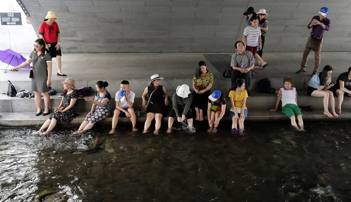 Warga bermain air saat siang hari di Sungai Cheonggye, Seoul, Korea Selatan, Senin (23/7). Suhu udara terik sekitar 33-37 derajat Celcius di seluruh negeri. (AP Photo/Lee Jin-man)