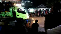 Truk melintas di tengah-tengah warga yang sedang asik nobar Timnas Indonesia U-23 vs Uzbekistan di kampung Sampora, Cisauk, Tangerang, Selasa (29/4/2024). (Bola.com/M Iqbal Ichsan)