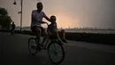 Seorang pria mengendarai sepeda di sepanjang East Lake, Wuhan, Provinsi Hubei, China, 5 Agustus 2020. Pencabutan karantina 76 hari di Wuhan terkait COVID-19 pada April lalu membawa kehidupan dan lalu lintas kembali macet. (Hector Retamal/AFP)