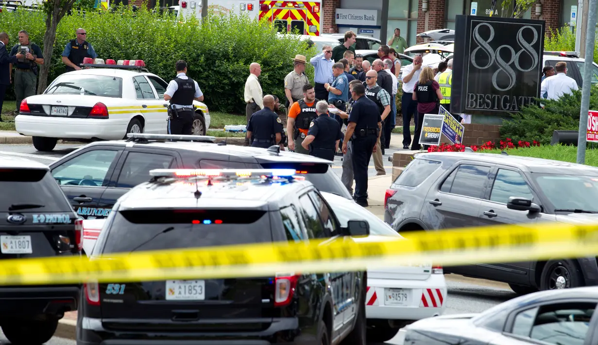 Pihak berwenang berada di pintu masuk gedung setelah penembakan di kantor surat kabar Capital Gazette di Annapolis, AS, Kamis (28/6). Insiden penembakan terjadi ketika staf redaksi sedang melakukan rapat sore hari. (AP/Jose Luis Magana)