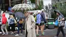 Don Kregsman (tengah) berjalan saat hujan turun di lapangan Pusat Tenis Nasional Billie Jean King, New York (29/8). Meski hujan, para penonton tetap antusias menunggu pertandingan tenis tersebut. (AP Photo / Michael Noble)