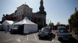 Sukarelawan berpakaian pelindung berjalan di halaman parkir Central Jamis Mosque Ghamkol Sharif di Birmingham, Inggris pada 24 April 2020. Saat masjid itu tutup selama Ramadan di tengah pandemi, tempat parkirnya digunakan menjadi kamar mayat sementara untuk korban corona Covid-19. (AP/Matt Dunham)