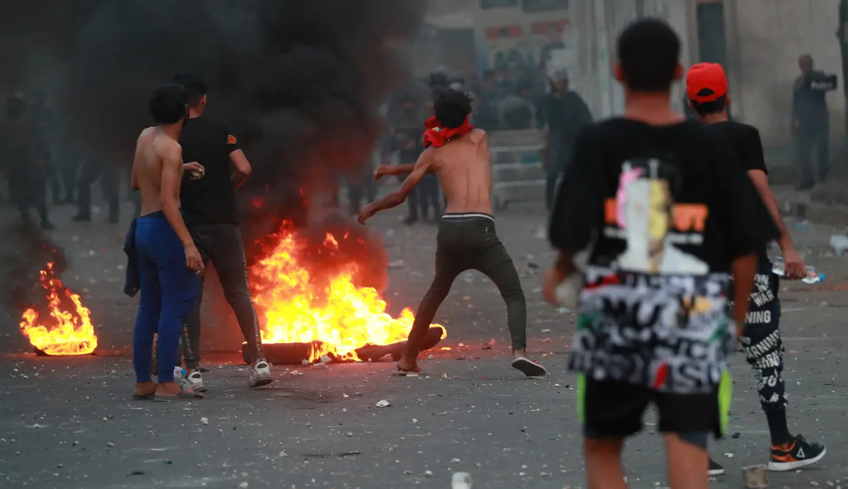 Demonstran antipemerintah bentrok dengan pasukan keamanan saat protes di dekat Alun-Alun Tahrir, Baghdad, Irak, Senin (27/7/2020). Perdana Menteri Irak mengatakan telah memerintahkan penyelidikan atas pembunuhan dua demonstran antipemerintah. (AP Photo/Hadi Mizban)