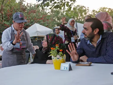 Seorang anak down syndrome Abdel Rahman melayani pelanggan di kedai kopi Sucet  selama festival "Sham gather us" di Damascus (11/7). Enam belas anak laki-laki dan perempuan down syndrome bekerja di Cafe Sucet melayani pelanggan. (AFP Photo/Louai Beshara)