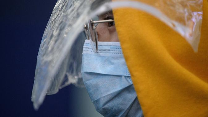 Penumpang memakai masker dan pelindung plastik darurat sebagai tindakan pencegahan terhadap virus corona COVID-19 setelah mendarat di bandara internasional Hong Kong (19/3/2020). Covid-19 yang menginfeksi lebih dari 200.000 orang terus menimbulkan kekhawatiran. (AFP/Anthony Wallace)