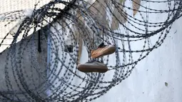 Sepasang sepatu di kawat berduri di penjara Mulhouse (Maison d'arret), Prancis timur (22/10/2021). Penjara Mulhouse mirip dengan penjara county di Amerika Serikat yang menahan tahanan kurang dari satu tahun. (AFP/Frederick Florin)