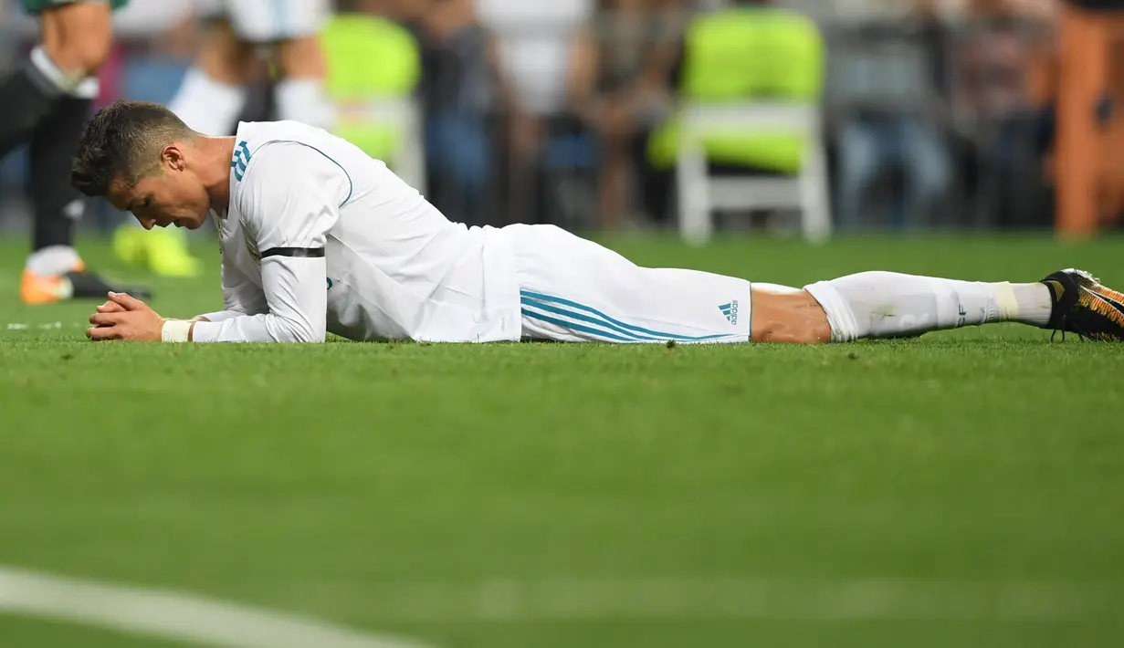 Penyerang Real Madrid, Cristiano Ronaldo berbaring di lapangan seusai kehilangan satu gol pada laga pekan lima La Liga melawan Real Betis di Santiago Bernabeu, Rabu (20/9). Real Madrid menyerah di tangan Real Betis 0-1. (GABRIEL BOUYS/AFP)