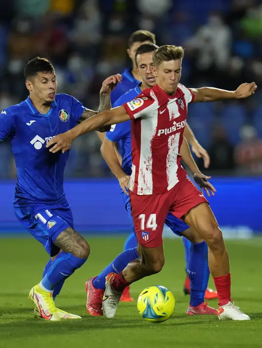 Gelandang Atletico Madrid, Marcos dan bek Getafe, Mathias Olivera berebut bola pada laga pekan keenam Liga Spanyol di Stadion Coliseum Alfonso Perez, Rabu (22/9/2021) dini hari WIB. Luis Suarez memborong dua gol saat Atletico Madrid mengalahkan Getafe 2-1. (AP Photo/Manu Fernandez)