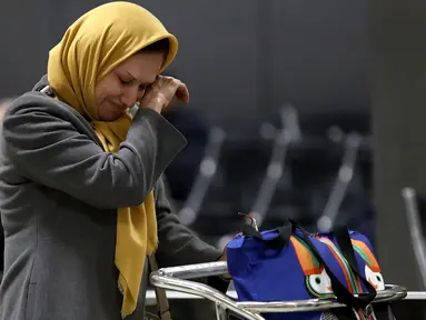 Wanita muslim menangis terharu setelah berpergian dari Addis Ababa, Ethiopia setibanya ia di Bandara Dulles, Washington, Senin (6/2). Sejumlah warga muslim sempat tidak dapat masuk AS akibat kebijakan imigrasi Donald Trump. (Win McNamee/Getty Images/AFP)
