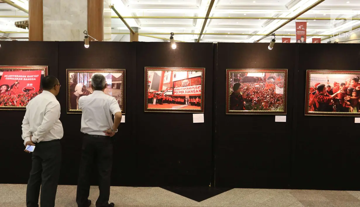 Dua pengunjung melihat pameran foto sejarah PDIP di JCC, Jakarta, Rabu (10/1). Pameran foto tersebut merupakan rekam jejak perjalanan PDIP di HUT yang ke-45. (Liputan6.com/Angga Yuniar)