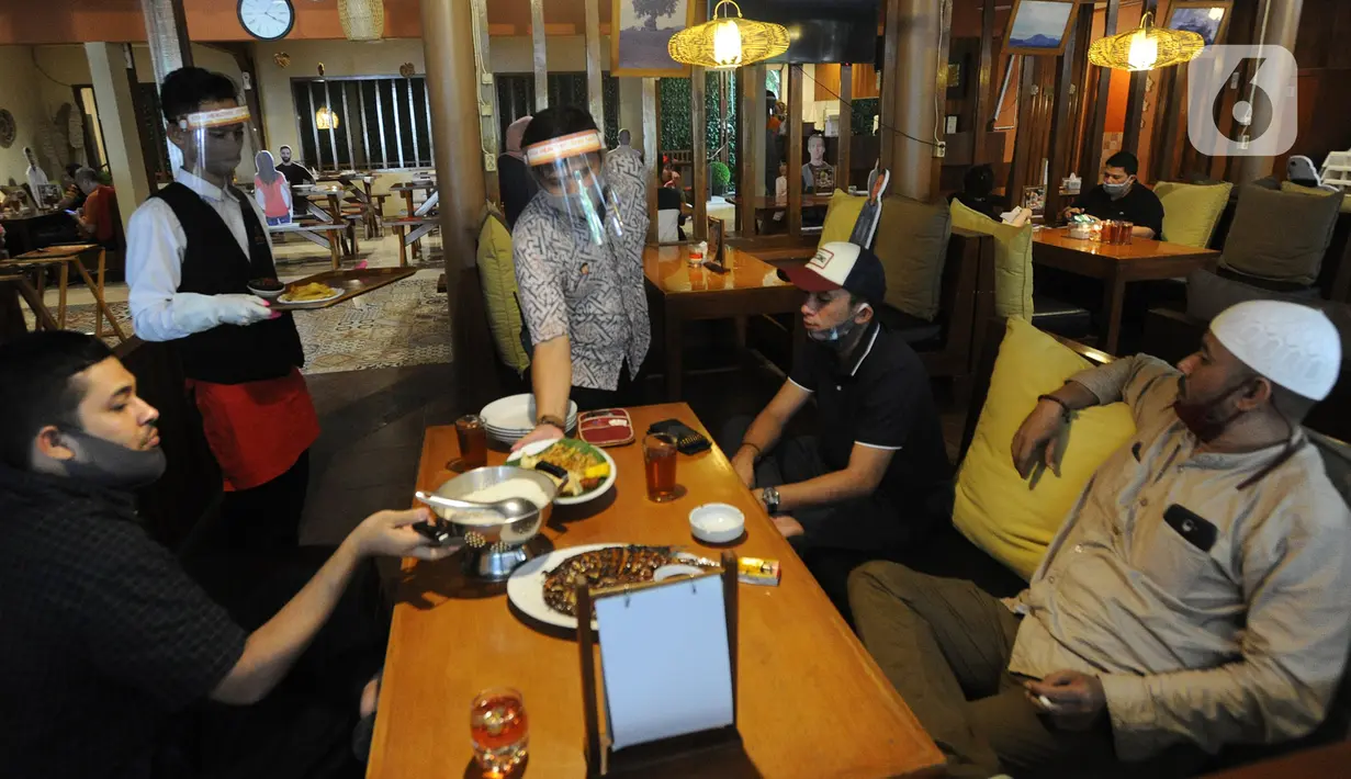 Pramusaji menggunakan pelindung wajah, masker dan sarung tangan di Rumah Makan Bumi Aki, Pajajaran, Kota Bogor, Minggu  (31/5/2020). Sejumlah restoran dan rumah makan di Bogor mulai membuka layanan makan di tempat dengan protokol kesehatan ketat guna mengatasi COVID-19. (merdeka.com/Arie Basuki)