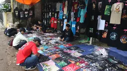 Penggemar Iwan Fals memilih kaos yang dijajakan pedagang di luar lokasi Konser Situs Budaya, kawasan Depok, Jawa Barat, Sabtu (3/3). Dalam Konser kali ini, Iwan Fals dan Band berkolaborasi dengan beberapa musisi. (Liputan6.com/Arya Manggala)