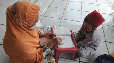 Seorang anak belajar mengaji di teras rumah seorang warga di kawasan Depok, Jawa Barat, Senin (16/8/2021). Beragam kegiatan seperti mengaji, menggambar, belajar mewarnai dan lain lain di masa pandemi dengan menerapkan prokes  ini dalam rangka mengisi waktu luang anak-anak. (merdeka.com/Arie Basuki)