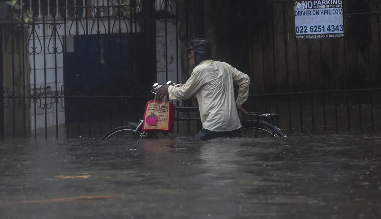 Seorang pria berjalan dengan sepedanya melalui jalan yang banjir saat hujan lebat di Mumbai, India, Rabu (9/6/2021). Mumbai terendam banjir usai diguyur hujan lebat. (AP Photo/Rafiq Maqbool)