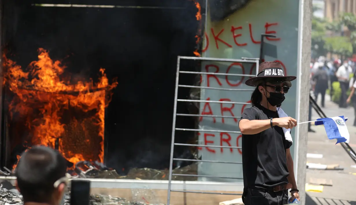 Mesin ATM bitcoin bernama Chivo terbakar selama protes terhadap kebijakan Presiden Nayib Bukele pada Hari Kemerdekaan di San Salvador, El Salvador, Rabu (15/9/2021). Ribuan warga Salvador berdemonstrasi menentang bitcoin, yang disahkan sebagai alat pembayaran oleh pemerintah. (MARVIN RECINOS/AFP)