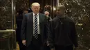 Presiden AS terpilih, Donald Trump dan Kanye West berjalan keluar dari lift usai melakukan pertemuan di Trump Tower, New York, Selasa (13/12). Menurut West, ia ingin membicarakan masalah-masalah multikultural dengan Trump. (Drew Angerer/Getty Images/AFP)