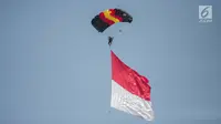 Penerjun payung membawa bendera Merah Putih saat perayaan HUT ke-73 Bhayangkara di Monas, Jakarta, Rabu (10/7/2019). Sebanyak 22 penerjun payung dari TNI dan Polri ikut menyemarakkan HUT ke-73 Bhayangkara. (Liputan6.com/Faizal Fanani)