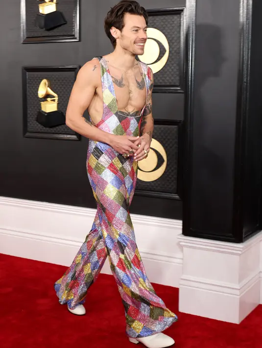 Penyanyi-penulis lagu Inggris, Harry Styles tiba untuk ajang Grammy Awards 2023 di Crypto.com Arena, Los Angeles, AS, Minggu Malam (6/2/2023) waktu setempat. Jumpsuit ini tak berlengan dan berpotongan dada rendah, sehingga menampilkan koleksi tato member One Direction. (Photo by Amy Sussman / GETTY IMAGES NORTH AMERICA / Getty Images via AFP)