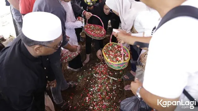 Keluarga dan para pelayat menabur bunga di area pemakaman.