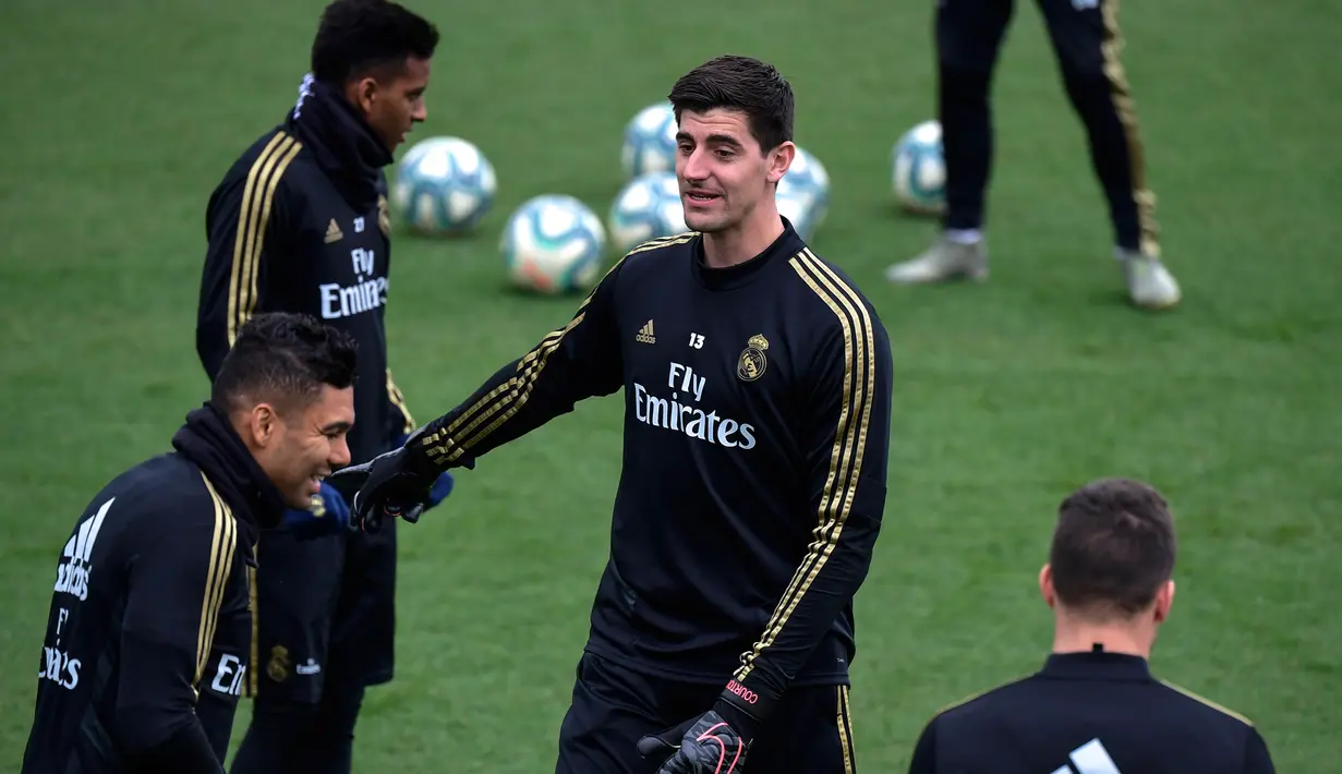 Kiper Real Madrid, Thibaut Courtois (tengah) dan gelandang Casemiro (kiri) berbincang saat menghadiri sesi latihan tim di fasilitas olahraga Real Madrid City di Madrid (17/12/2019). Real Madrid akan bertanding melawan Barcelona dalam laga El Clasico di Nou Camp. (AFP/Javier Soriano)