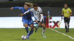 Gelandang Jerman, Jamal Musiala berusaha melewati pemain Islandia, Birkir Bjarnason dalam lanjutan laga kualifikasi grup J Piala Dunia 2022 di Reykjavik, Islandia, Kamis (9/9/2021). Jerman menang telak atas Islandia dengan skor 4-0. (AP Photo/Arni Torfason)