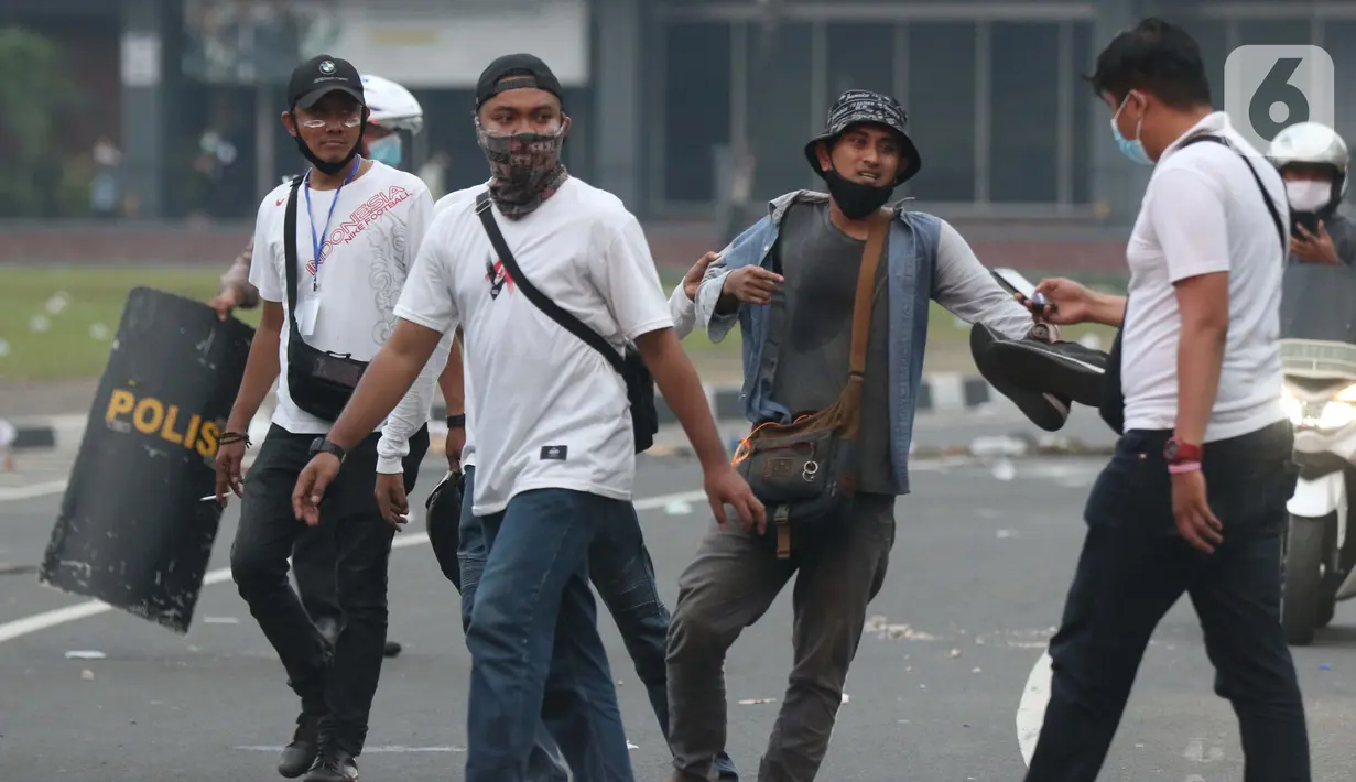 Polisi berpakaian kaus putih mengamankan seseorang yang dicurigai terlibat kericuhan di kawasan Tugu Tani, Jakarta, Selasa (13/10/2020). Sejumlah pemuda diamankan polisi karena dicurigai terlibat kericuhan di kawasan Tugu Tani. (Liputan6.com/Helmi Fithriansyah)